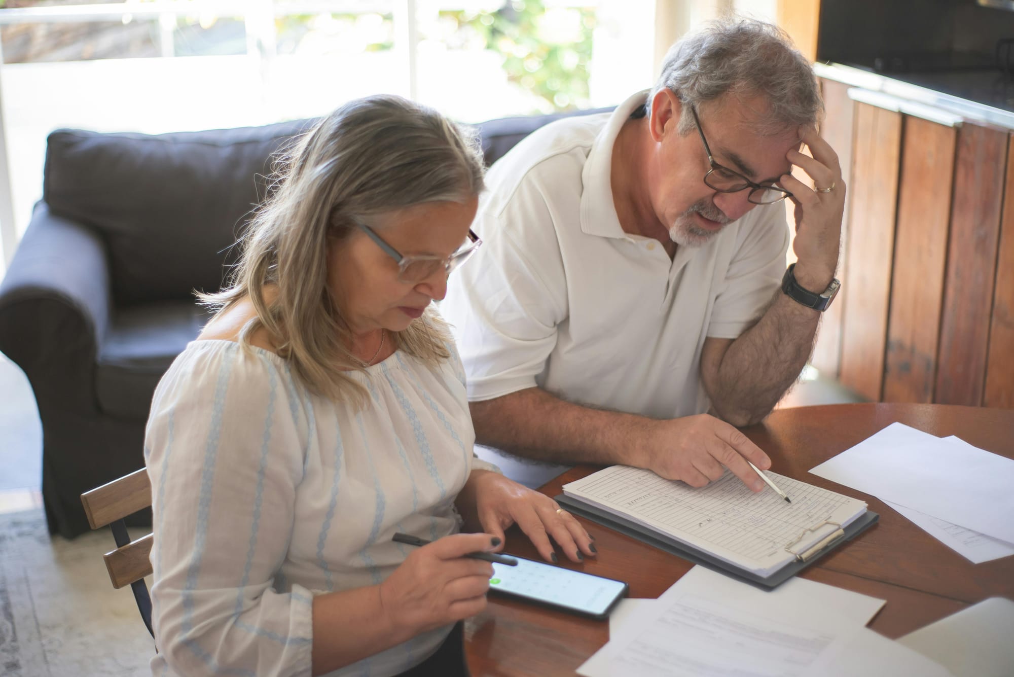 Two people reviewing documents while using a smartphone at a table