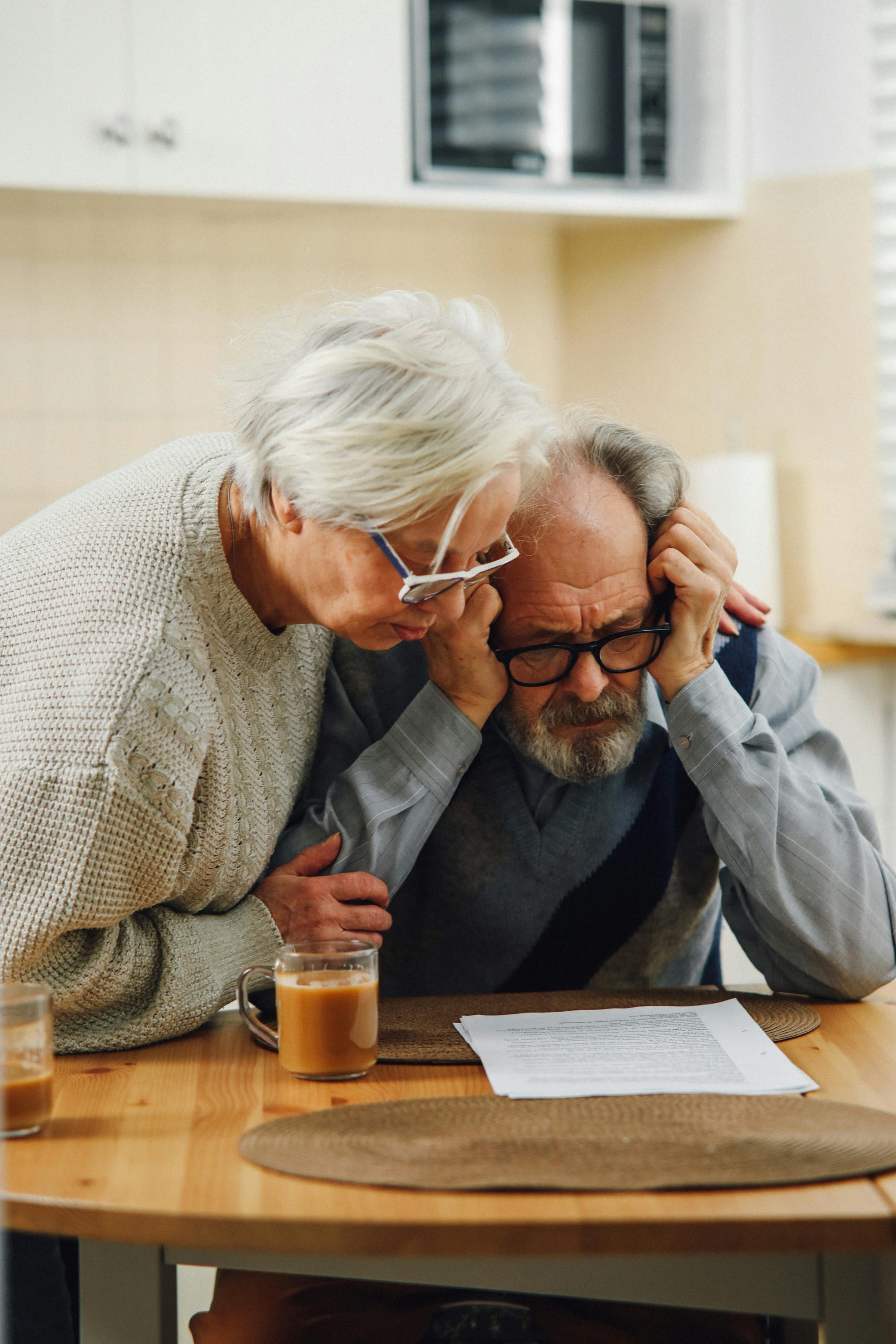 An older couple reviews paperwork together at a table while discussing next steps.