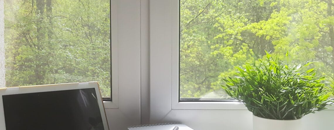 Peaceful workspace by a window with forest view and natural light.