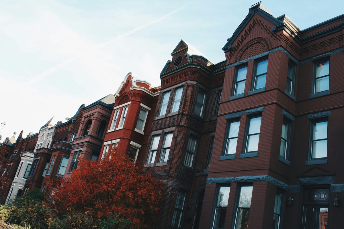 Red brick rowhouses along a Washington, D.C. residential street in daylight.