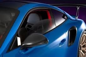 Close-up of a sleek blue sports car with racing seat, side mirror, and rear spoiler visible.