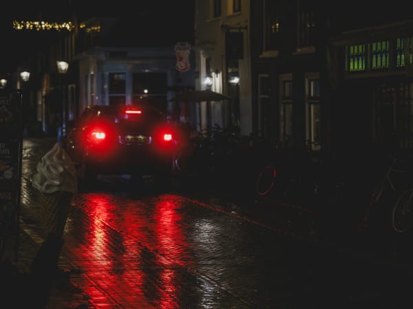 Car taillights reflecting on a wet city street at night