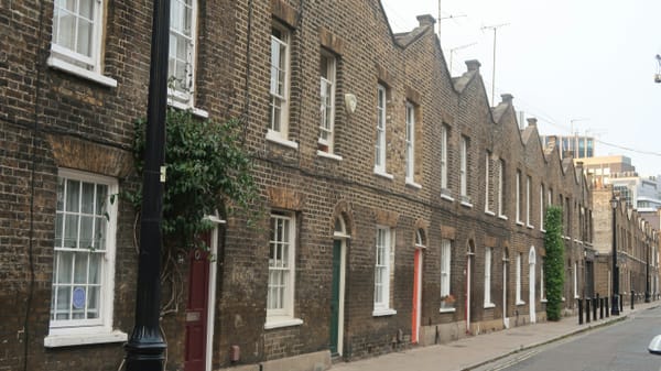 Row of older brick attached homes along a residential street.
